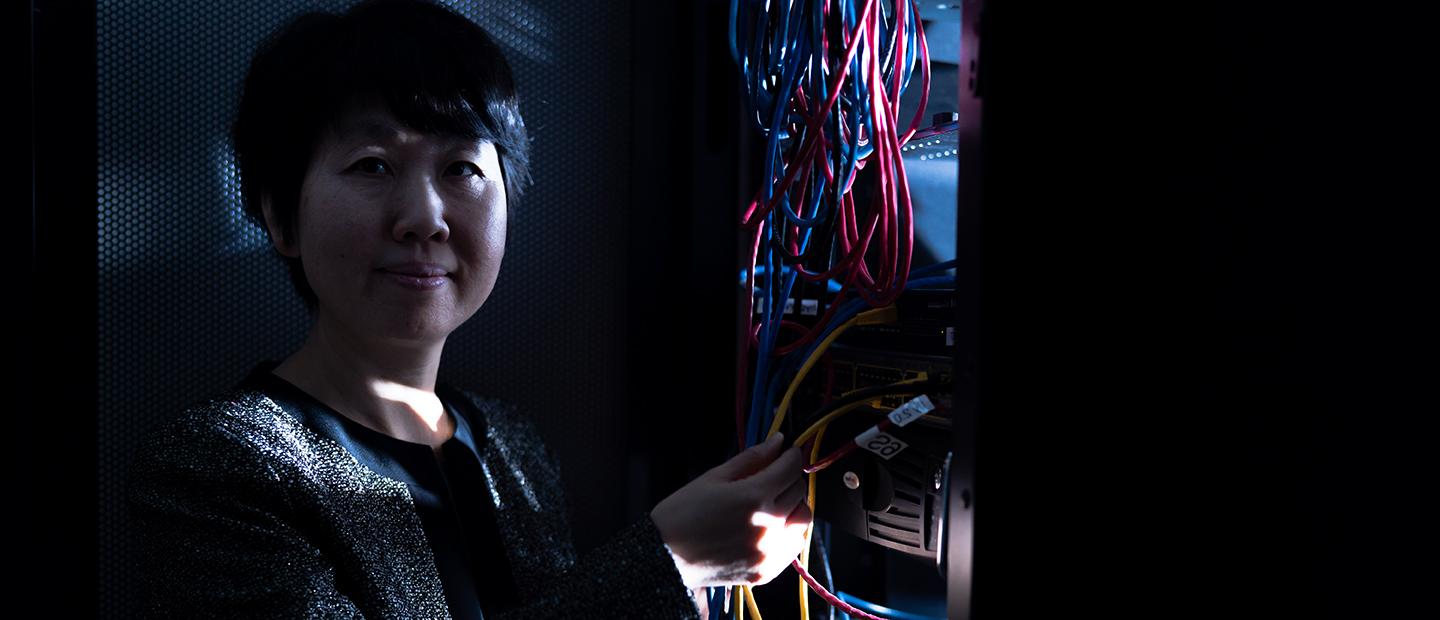 A woman holding the wires from a computer